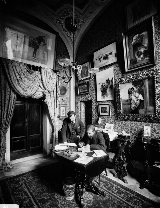 Fratelli Alinari, Vittorio Alinari in his studio at the Fratelli Alinari photographic factory in Via Nazionale in Florence. A copy of the painting “The Madonnina” by Roberto Ferruzzi hangs on the wall, 1899, silver gelatin dry glass plate negative, Alinari Archives-Alinari archive, Florence.